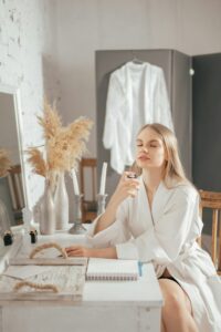 Beautiful happy smiling young blonde woman sitting with bottle of perfume in her hand lifestyle